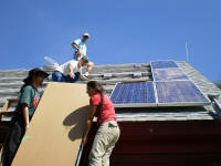 Topher and Barbara hefting a panel to the roof